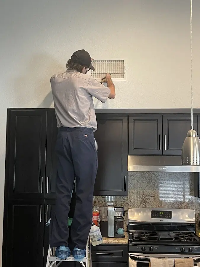 Technician inspecting an air vent during HVAC service in Winooski